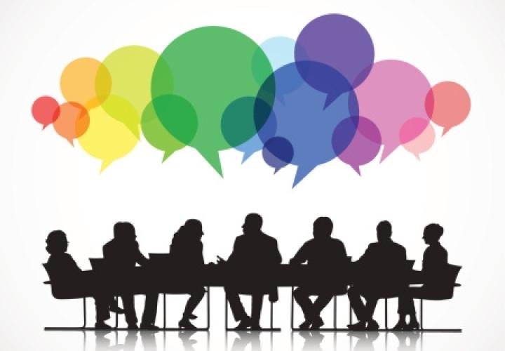 Individuals sitting around a table with chat bubbles overhead