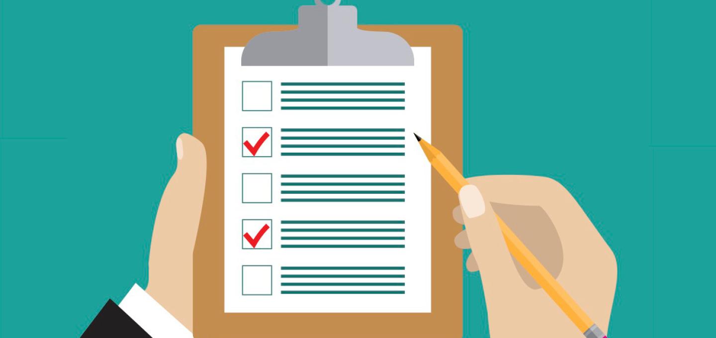 Hand holding a pencil checking off boxes on a checklist