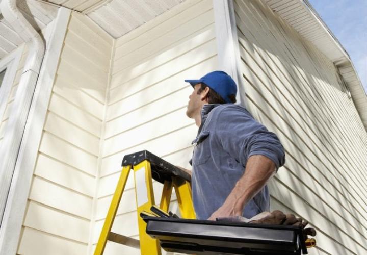 man looking up at roof with ladder and tools