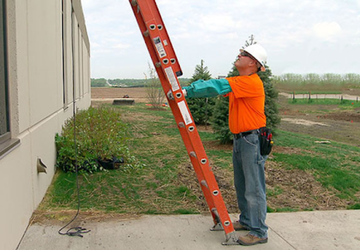 man stabilizing extension ladder on sidewalk