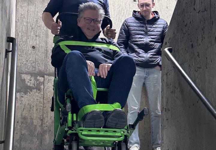 Man in Stryker evacuation chair being lifted down stairs