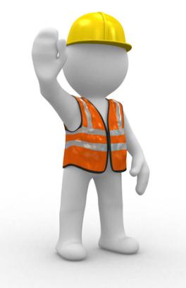An individual wearing a hard hat and reflectve vest is holding up a hand gesturing to stop
