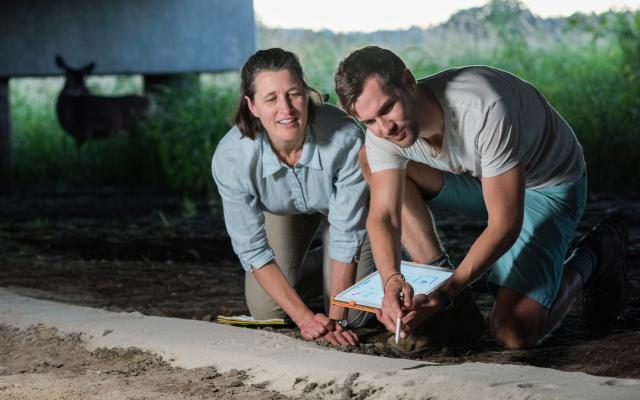 Students examining soil under a bridge