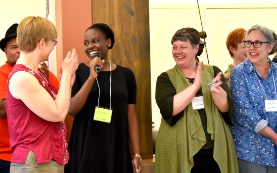 A student and faculty stand in a row, clapping at an event