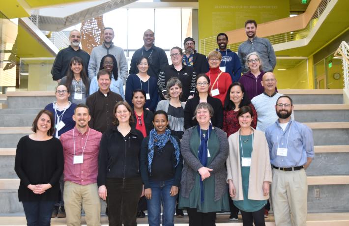 a group of 15 faculty stand together for a group photo