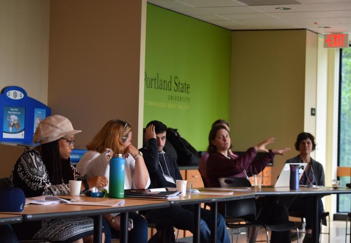 Faculty sit at a table at a conference, talking