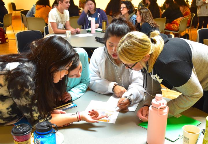 Students at a table look at a paper at new student orientation