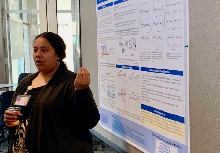 Student stands at a poster for a presentation