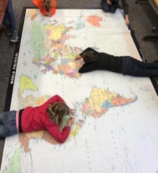 Two kids laying on their stomachs on Giant World Map