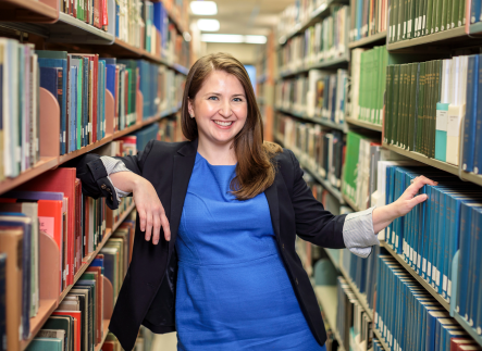 Female student in-between bookshelf