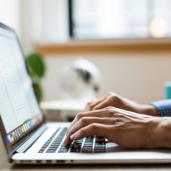 Hands typing on a laptop computer.