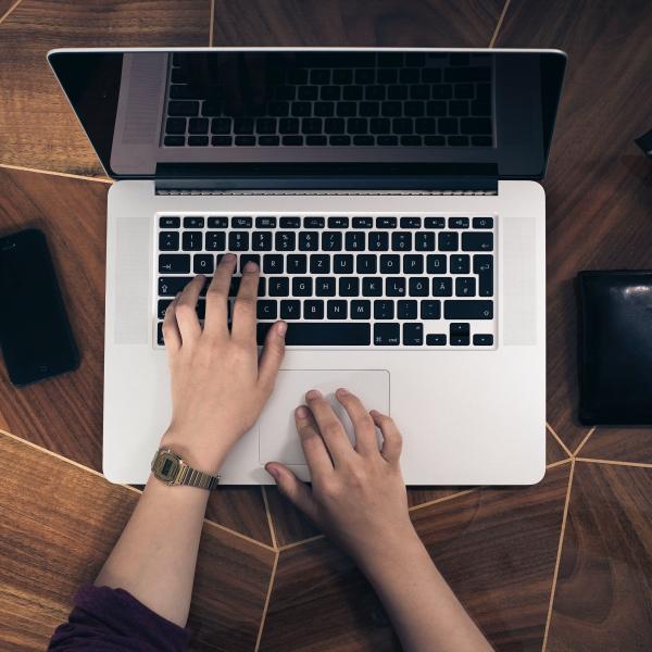 Two hands typing on a macbook laptop computer.