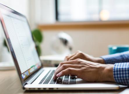 Hands typing on a laptop computer.
