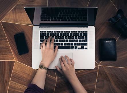 Two hands typing on a macbook laptop computer.