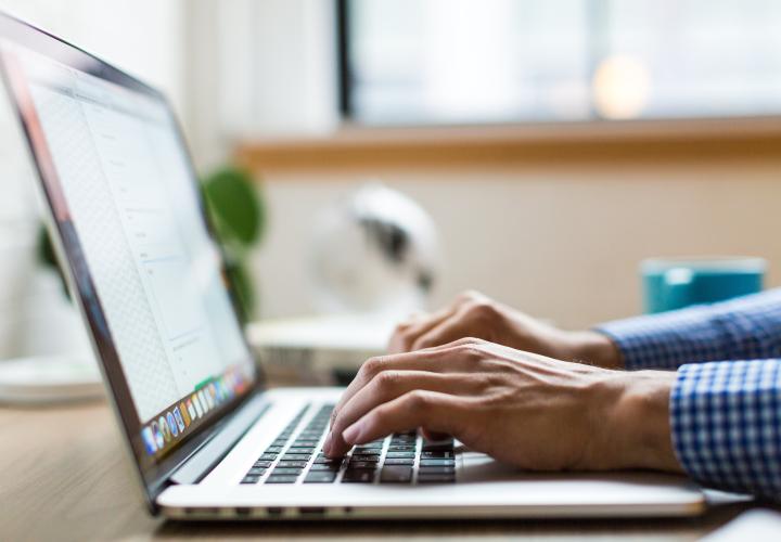 Hands typing on a laptop computer.