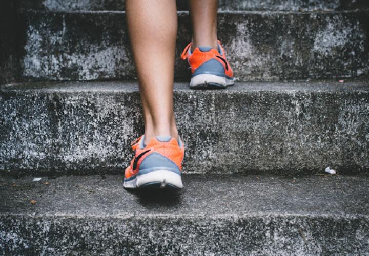 Back of somebody's athletic shoes walking up stairs.