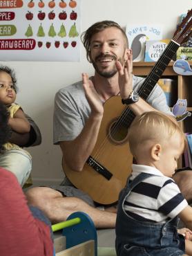 Teacher playing guitar with children
