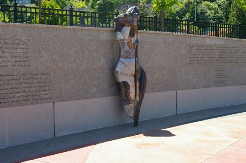 Bronze sculpture of woman in front of wall