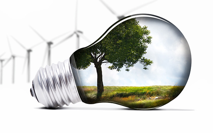 lightbulb with tree inside, faded wind farm in background