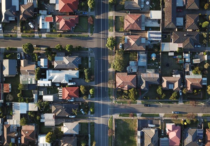 Birds-eye-view of a neighborhood, with many houses and trees along the streets.