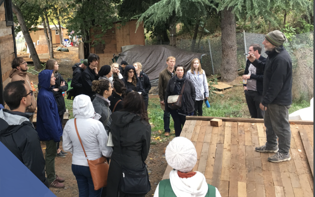 A group of people stand outside at Hazelnut Grove having a conversation. 