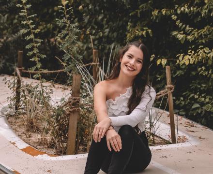 Mia, Honors student, sitting in front of a garden