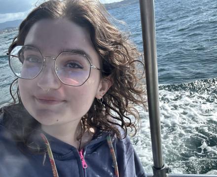 Chayse on a boat with the ocean behind