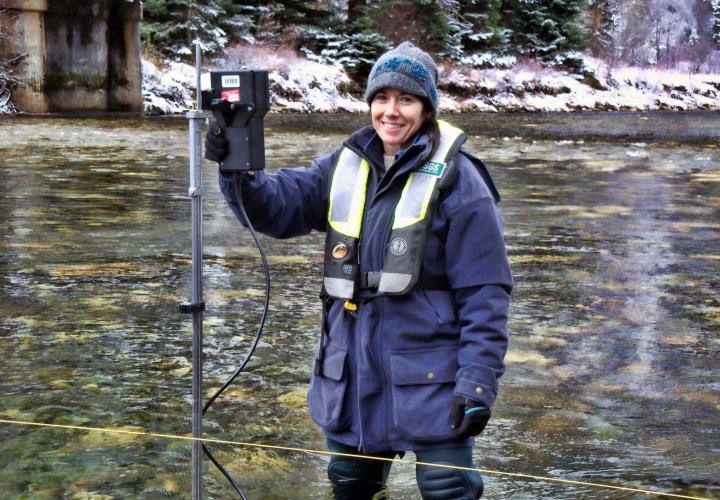 A USGS employee stands in a stream in Idaho with streamflow measurement equipment.