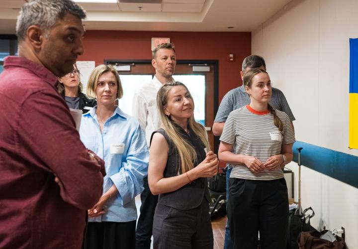 A group of attendees, some wearing name badges, stand together in conversation during the seminar, with a Ukrainian flag visible on the wall.