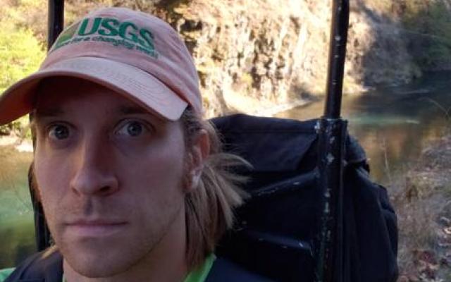 Photo of Matt Yates, a caucasian man with sholder length hair wearing a red baseball cap