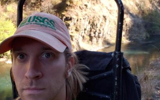 Photo of Matt Yates, a caucasian man with sholder length hair wearing a red baseball cap