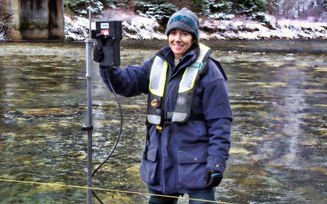 A USGS employee stands in a stream in Idaho with streamflow measurement equipment.