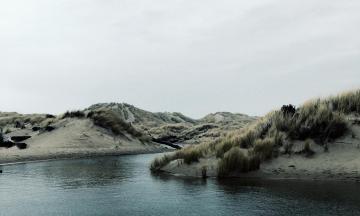 Body of water near mountain under white sky by Jacob Mehringer