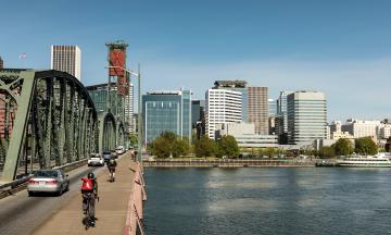 Biker on Hawthorne Bridge with Portland cityscape and Willamette River
