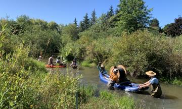 Researchers are dragging a canoe with equipment through a stream