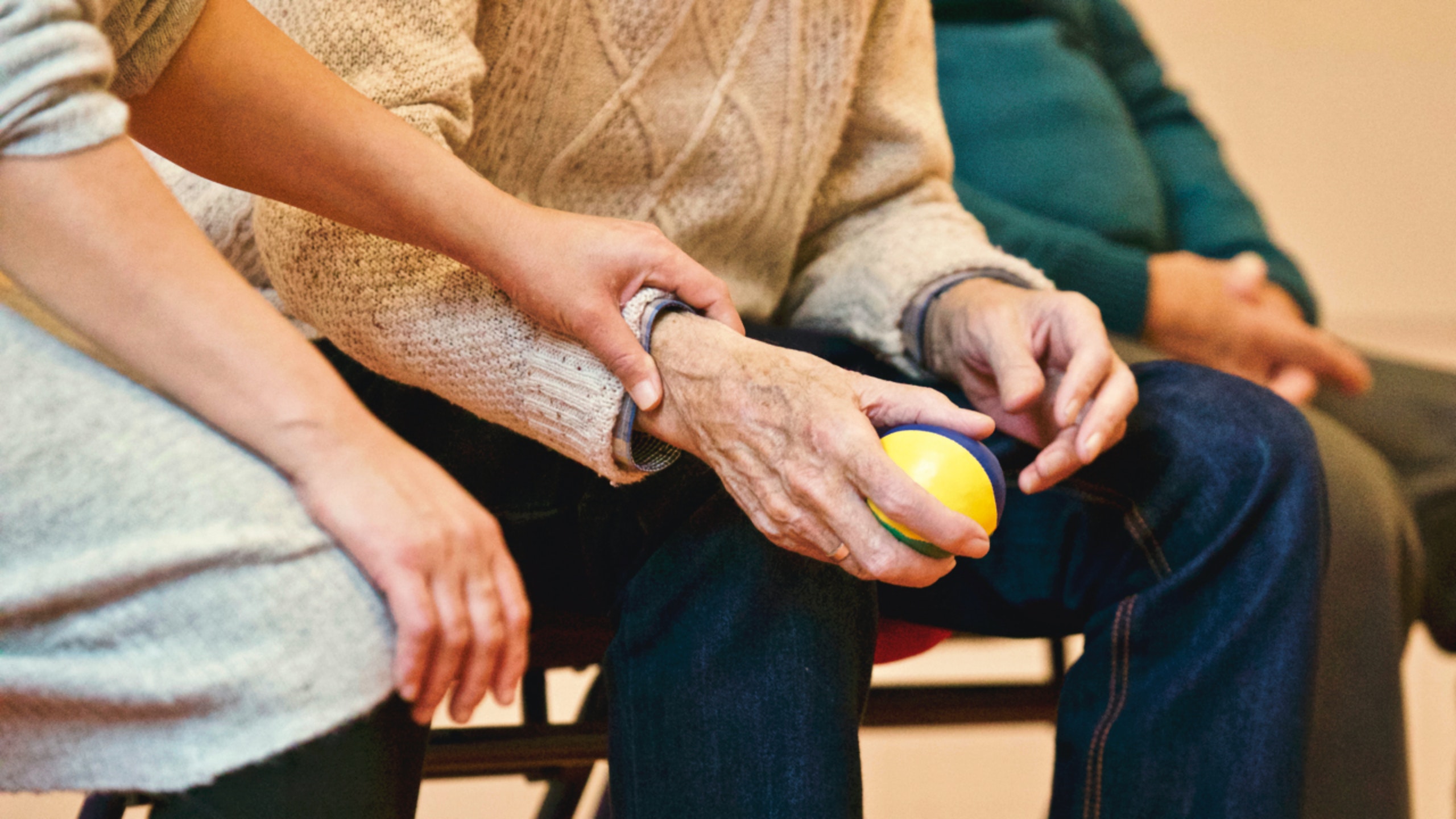 Younger hand holding an older hand holding a ball