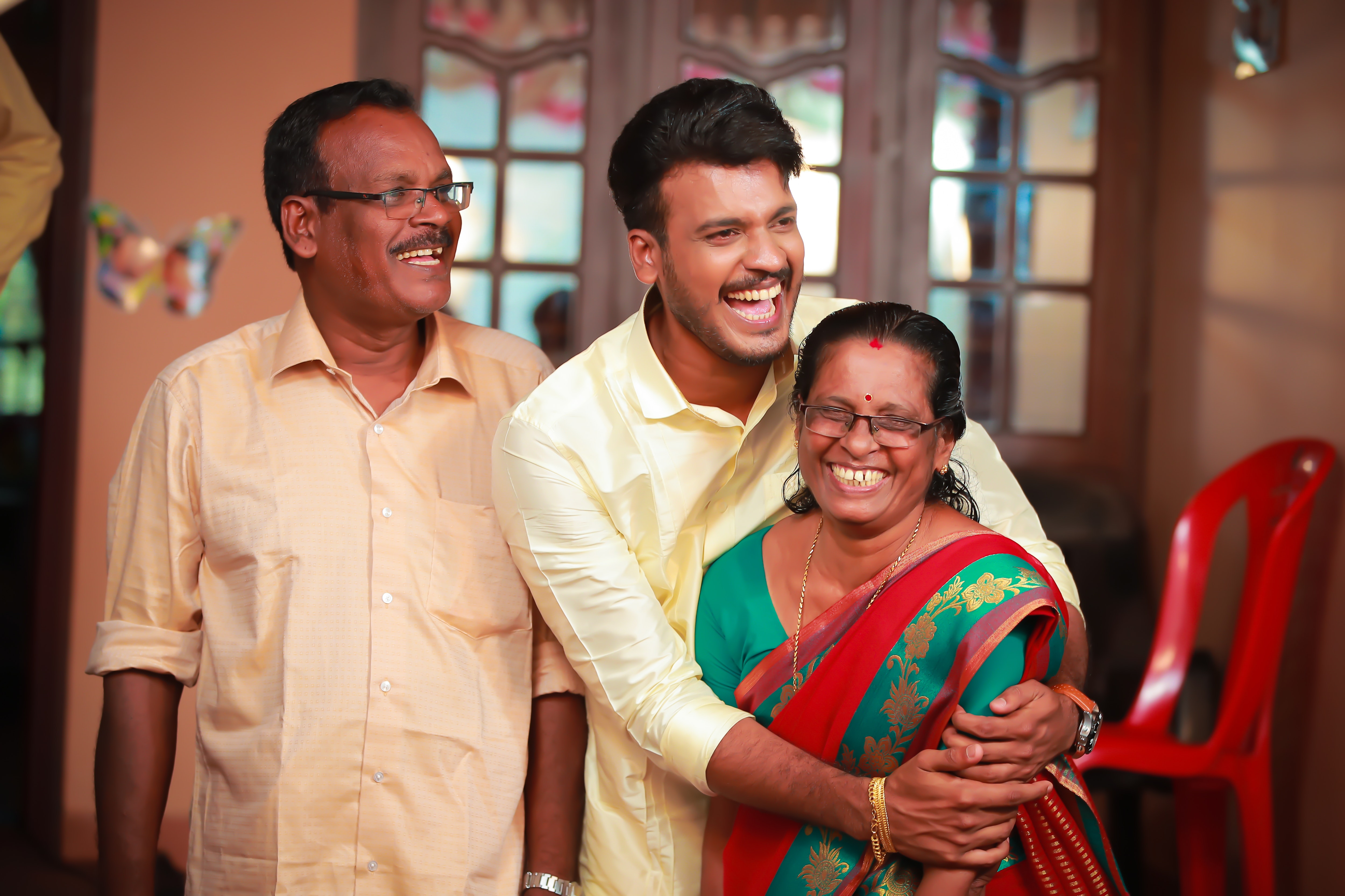 Indian student hugging his smiling parents