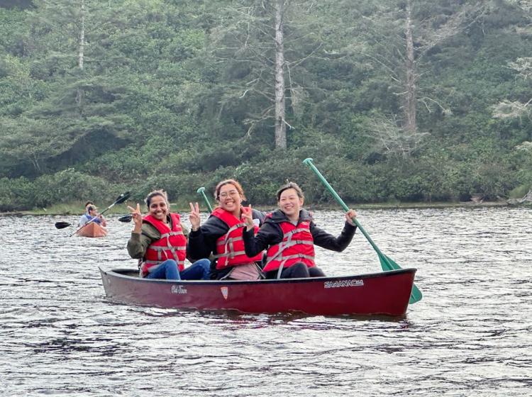 Three people in a canoe on the water poses for a photo.