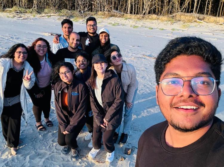 Group of people pose for a selfie on the beach.