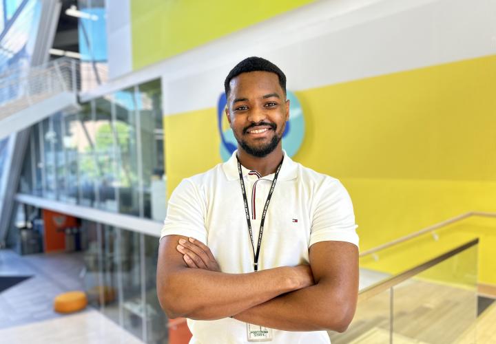 Student stands and poses for a headshot in the Karl Miller Center Atrium.