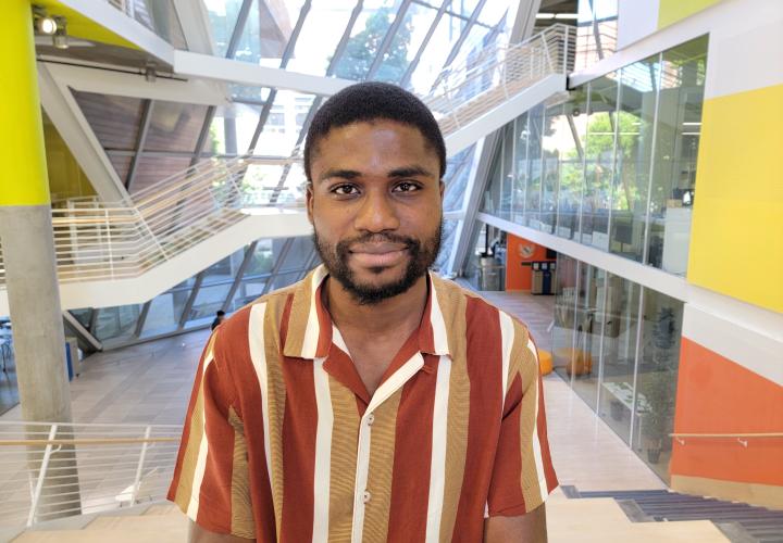 Student stands and poses for a headshot in the Karl Miller Center Atrium.