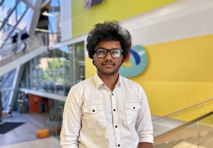 Student stands and poses for a headshot in the Karl Miller Center Atrium.