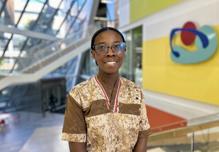 Student stands and poses for a headshot in the Karl Miller Center Atrium.
