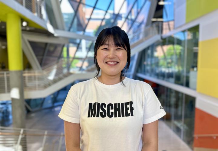 Student stands and poses for a headshot in the Karl Miller Center Atrium.