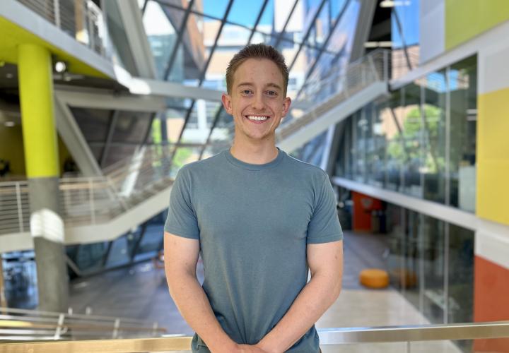 Student stands and poses for a headshot in the Karl Miller Center Atrium.
