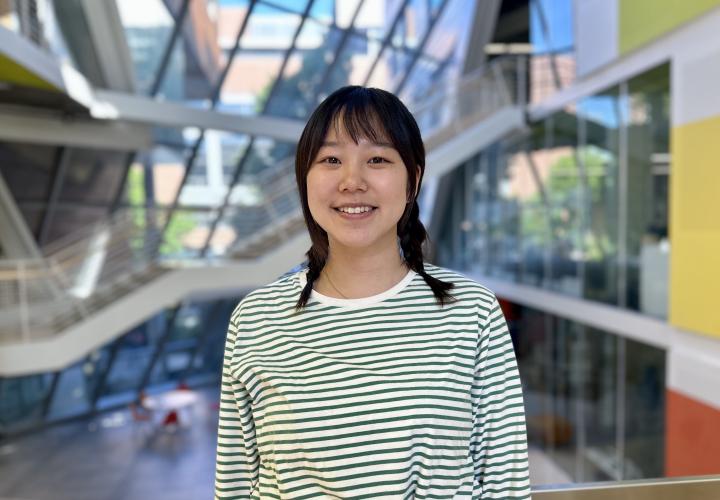 Student stands and poses for a headshot in the Karl Miller Center Atrium.