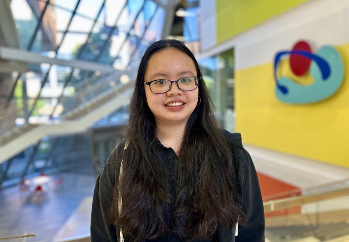 Student stands and poses for a headshot in the Karl Miller Center Atrium.
