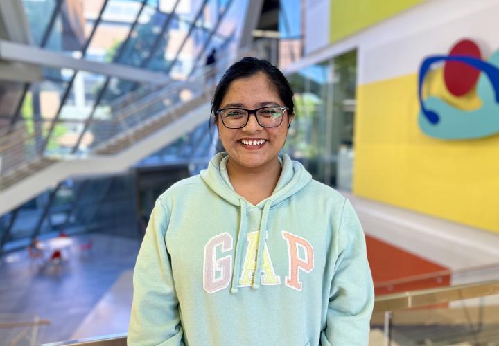 Student stands and poses for a headshot in the Karl Miller Center Atrium.
