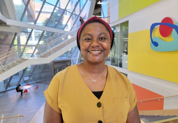 Student stands and poses for a headshot in the Karl Miller Center Atrium.