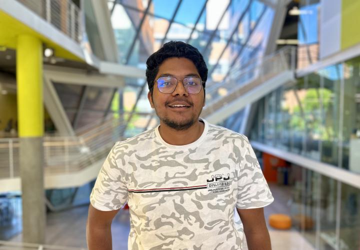 Student stands and poses for a headshot in the Karl Miller Center Atrium.